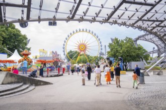 Lively amusement park with Ferris wheel and lots of people strolling around, Olympic Park, Munich,