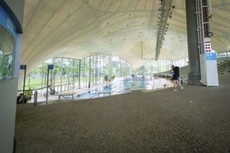 View into an indoor swimming pool with large windows that bring a lot of light onto the pool,