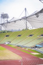 Partial view of a modern stadium with green rows of seats and red running track, Olympic Park,