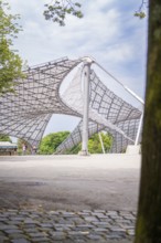Modern architectural structure with lattice roof and a tree in the foreground, Olympiapark, Munich,