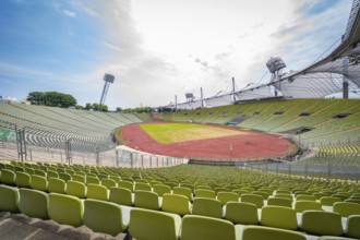 Empty stadium with green seats and a red running track under a bright sky, Olympiapark, Munich,