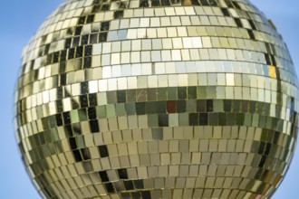 Golden disco ball, small mirrors, distributed like a mosaic, reflect light and create lighting