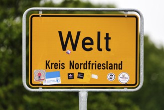Place name sign world, inscription, many stickers, Eiderstedt peninsula, North Frisia, Germany