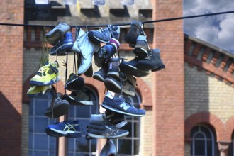 Shoes hanging on a leash in the courtyard of a residential home for addicts, each shoe a reminder