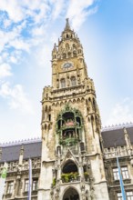 Detailed tower of the town hall with clock and figures under a blue sky, Munich, Germany