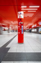 Empty area in the underground station with red design element and central information stand,