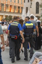 Two security guards in uniforms walking through a busy street, Munich, Germany