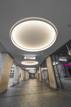 Modern shopping arcade with illuminated ceiling lights and shops, Munich, Germany