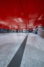 Modern underground station with red design and an empty, spacious area, Munich, Germany