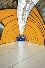 Orange tunnel with symmetrical structures and tiles leading into the depths, Marienplatz, Munich,