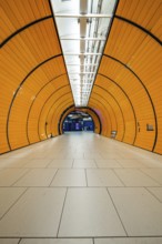 Long, illuminated underground railway tunnel in bright orange, leading into the distance,