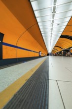 Long underground corridor with orange-coloured walls and strong lines leading into the depths,