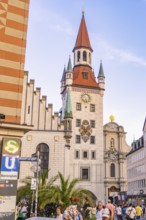 Historic tower with clock in a lively urban environment under a clear sky, Munich, Germany