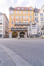 Historic city hotel with a striking orange-coloured façade and inviting entrance, Munich, Germany