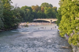 River with people crossing the bridge and relaxing on the bank, surrounded by green nature, Munich,
