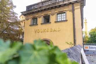 Historic public swimming pool with yellow façade, traditional architecture and surrounded by trees,