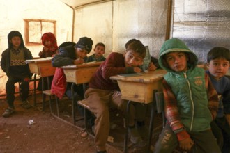 Syrian refugee children sitting inside a tent classroom, receiving basic education despite