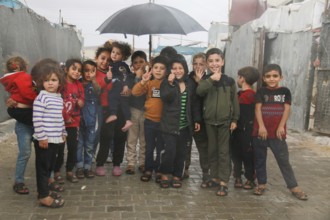 Syrian children inside the refugee camp taking a group photo under the rain on World Children's Day