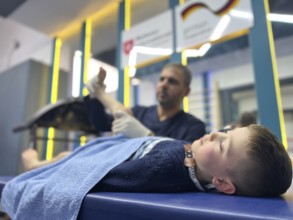 A displaced Syrian child receiving physical therapy from a physiotherapist after a war injury.