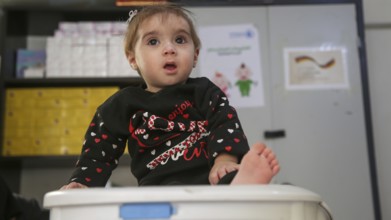 A doctor examining a refugee child for malnutrition in the camp using weight and height measurement