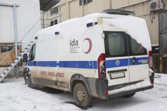 An ambulance parked at the entrance of an informal refugee camp, prepared for any medical