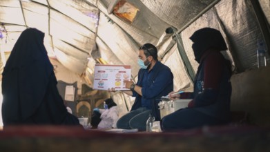 A community health worker giving instructions to refugees on how to deal with the cholera outbreak