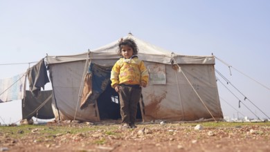A Syrian girl stands in front of her tent in a refugee camp. World Children's Day. Aleppo, Syria.
