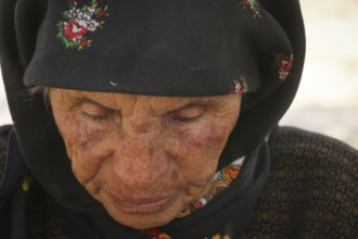 An elderly Syrian refugee looks worn out by war, as displaced people endure difficult conditions in