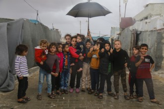 Syrian children inside the refugee camp taking a group photo under the rain on World Children's Day
