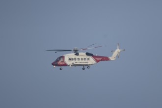 Sikorsky S-92A helicopter of the UK HM Coastguard flying in a blue sky, England, United Kingdom