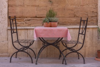 A small table and two chairs in the street in front of a restaurant, Tuscany, Italy
