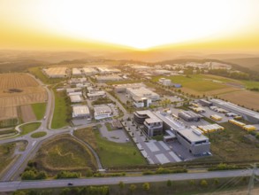 Industrial park at sunset, with symmetrical streets and a mixture of fields and buildings,