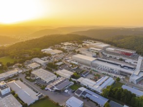 Large industrial complex at sunset, embedded in a hilly landscape with forests, industrial area