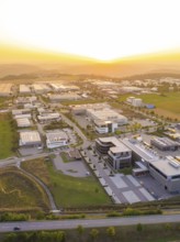 Large industrial estate at sunset, surrounded by green fields and modern structures, industrial