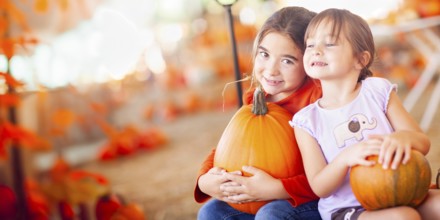 Two girls holding their pumpkins at A pumpkin patch on a fall day