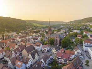 Panorama of an urban village with church and green hills in the evening light, Nagold, district of