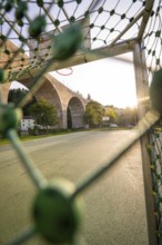 View through a basketball net onto a stone bridge in the morning light, Nagold, district of Calw,
