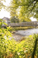 River with a bridge flanked by green trees on a sunny day, Nagold, district of Calw, Black Forest,