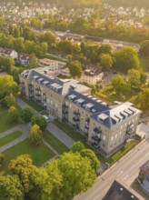 Large residential building with surrounding trees and streets, captured in autumnal scenery from