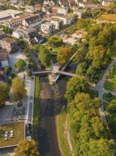 Drone shot of a river with bridges and surrounding trees in autumn colours in an urban environment,