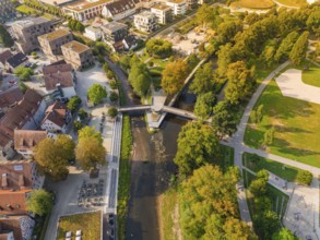 Aerial view of a park with river and bridge, surrounded by autumn leaves and buildings, Nagold,