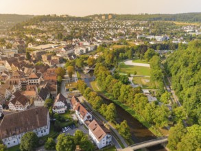 River runs through a town in autumnal landscape, surrounded by lush greenery and town buildings,