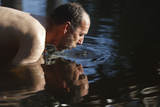 Man in the water during body care while travelling, Müritz National Park, Mecklenburg-Western