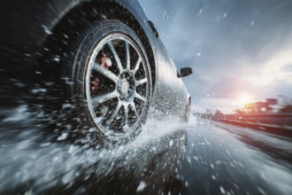 Car drives fast on a wet road, motorway, motorway and generates splash water, risk of accident due