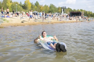 Festival visitor Sven lies on an air mattress in Lake Störmthal at the Highfield Festival on