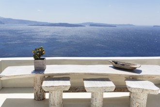Wooden table on a white terrace by the sea, view of the caldera, Oia, Thira, Santorini, Cyclades,