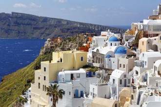 White and colourfully painted holiday homes, orthodox churches with blue domes on the edge of the