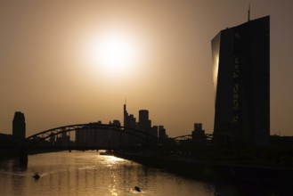 The sun is high above the European Central Bank (ECB) and the Frankfurt banking skyline, Frankfurt