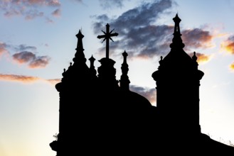 Silhouette of the towers and crucifix of an old baroque church in Ouro Preto during sunset
