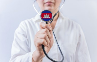 Female doctor holding stethoscope with Cambodia flag. National health system of Cambodia